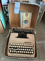 Open tan portable Smith and Corona typewriter inside a case with visible keyboard and carriage, showing the brand logo and keys.