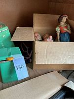 Snow White and dwarfs statues partially packed in a cardboard box with green kitchen canisters.