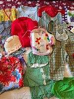 Overview photo showing vintage children's clothing including sweaters, rompers, dresses, and hats in multiple colors and patterns.
