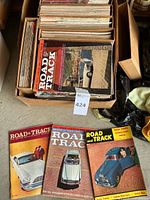 Box full of vintage Road & Track magazines with colorful car covers from 1950s-60s.