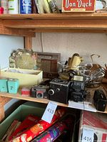 Shelf view showing vintage cameras, flash units, Federal wooden radio, and Sunbeam mixer with accessories