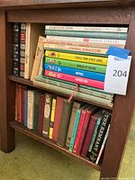 Two shelves of books showing a variety of vintage hardcover books including illustrated encyclopedia volumes and children's books.