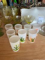 Photo showing yellow-green vintage stem glasses, frosted cactus glasses, and striped fabric hat on table.