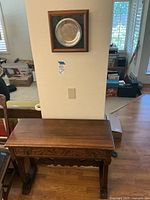 Framed sterling silver University of Arizona plate mounted above wooden console table