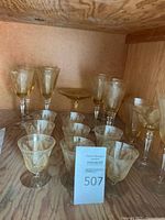 Group photo showing several etched yellow vintage glasses including stemmed wine glasses, goblets, and a plate.