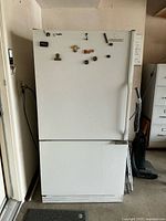 Front view of white KitchenAid refrigerator with magnets on door and handle on right side.