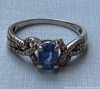 Front view showing oval blue gemstone and pavé shoulders