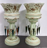 Pair of antique Victorian glass lustres showing front view with floral gold painted designs and colored hanging glass prism drops.