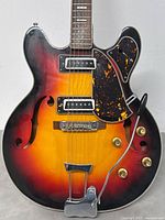 Close-up of guitar body showing sunburst finish, f-holes and dual single-coil pickups