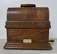 Front view of closed oak wood domed case with Edison logo on front