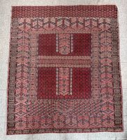 Full view of the antique handwoven rug laid flat on a tile floor showing complete geometric pattern design and colors.