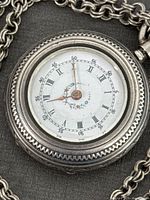 Close-up of white dial with Roman numerals and minute markers, floral center design, watch hands.