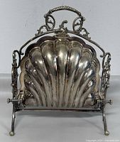 Front view showing shell-shaped silver plated body on scroll feet and decorative handle