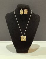 Front view of necklace and earrings displayed on black velvet stand showing rectangular pendants with silver bar accents.