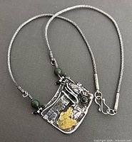 Full view of necklace including silver-tone chain and pendant with jade and gold-tone accents