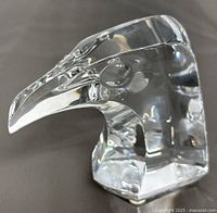 Side view of clear crystal eagle head paperweight showing detailed beak and eye with faceted base.