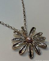 Close-up image showing the flower pendant with pearl center on polished silver 23-inch chain.