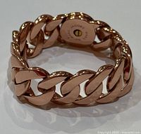 Close-up image of chunky rose gold tone chain link bracelet showing toggle clasp with Marc By Marc Jacobs branding.