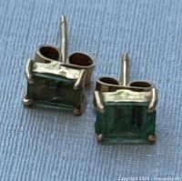 Pair of emerald stud earrings on blue cloth