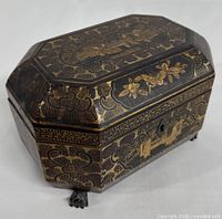 Closed view of octagonal lacquered tea caddy showing gilt cloud and floral pattern