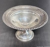 Front perspective view of footed bowl on black background showing pierced gallery rim and pedestal base