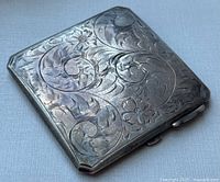 Front view showing the ornate engraved floral and scroll pattern on the sterling silver compact.