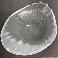 Top angled view of the frosted crystal ashtray showing swirling, wave-like ridges and glossy scalloped edges.