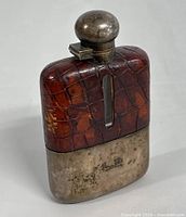 Front view of vintage hip flask showing crocodile skin upper section and tarnished sterling silver bottom with initials 'L.D.'