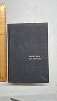 Front cover of black hardcover book titled 'Einstein on Peace' with ruler for size reference.