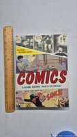 Front cover of book 'Comics: A Global History, 1968 to the Present' with ruler for size reference.
