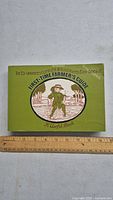 Front cover of the First-time Farmer's Guide book showing title and illustration of a farmer on a green background with a measuring ruler for scale.