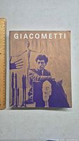 Front cover of the Giacometti art book showing the artist and his sculptures.