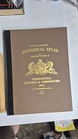 Front cover of the historical atlas showing the title and decorative gold emblem.