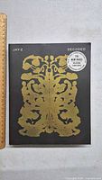 Front cover of Jay-Z Decoded showing gold inkblot design and promotional sticker