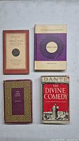 Top view of four vintage books laid out flat showing front covers of 'Selected Tibetan Plays,' 'Julius Caesar,' 'The Greek Myths,' and 'The Divine Comedy'.