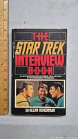 Front cover of the Star Trek Interview Book by Allan Asherman showing title, photo of three Star Trek characters, and author name.
