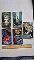 Front view of five Star Trek paperback books arranged side by side with a ruler for scale.