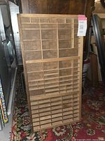 Front view of the antique wooden letter press tray showing compartments of various sizes arranged vertically.