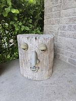 Front view showing the sculpted sleepy eyes, nose, and lips on the log surface.