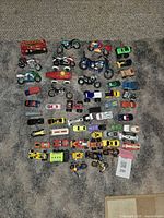 Top-down photo showing entire collection of assorted toy vehicles including motorcycles, cars, trucks, and a red double decker bus.