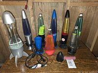 Seven lava lamps and spare parts arranged on wooden surface