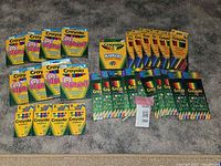 Photo showing 9 packages of Crayola markers, 17 packages of colored pencil crayons, and 4 packages of crayons arranged on carpeted floor.