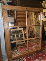 Front view of the farmhouse window pane mirror leaning against a wall showing its six rectangular mirrored panes and rustic wooden frame.