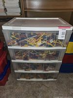 White plastic storage organizer with four full drawers filled with assorted KNEX parts visible through the translucent drawers.