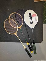 Four badminton rackets laid side by side showing different materials and handles, highlighting the vintage look.