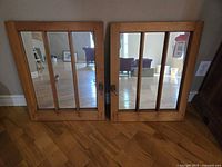 Pair of pine window pane mirrors with three vertical panes each, laid on wooden floor, showing side metal latch hardware.