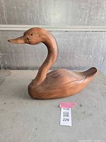 Side view of the wooden carved goose showing detailed neck and beak shape, along with the wood grain texture.
