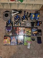 Overview of GameCube console, controllers, arcade-style controllers, microphones, memory cards, games, Game Boy Color consoles and cartridges on carpet