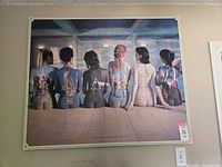 Full view of the large Pink Floyd art poster showing seven nude women with album cover paintings on their backs in a tiled room.