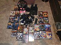 Overhead photo showing all games spread out along with the V3 steering wheel and pedals plus controllers and a remote control.